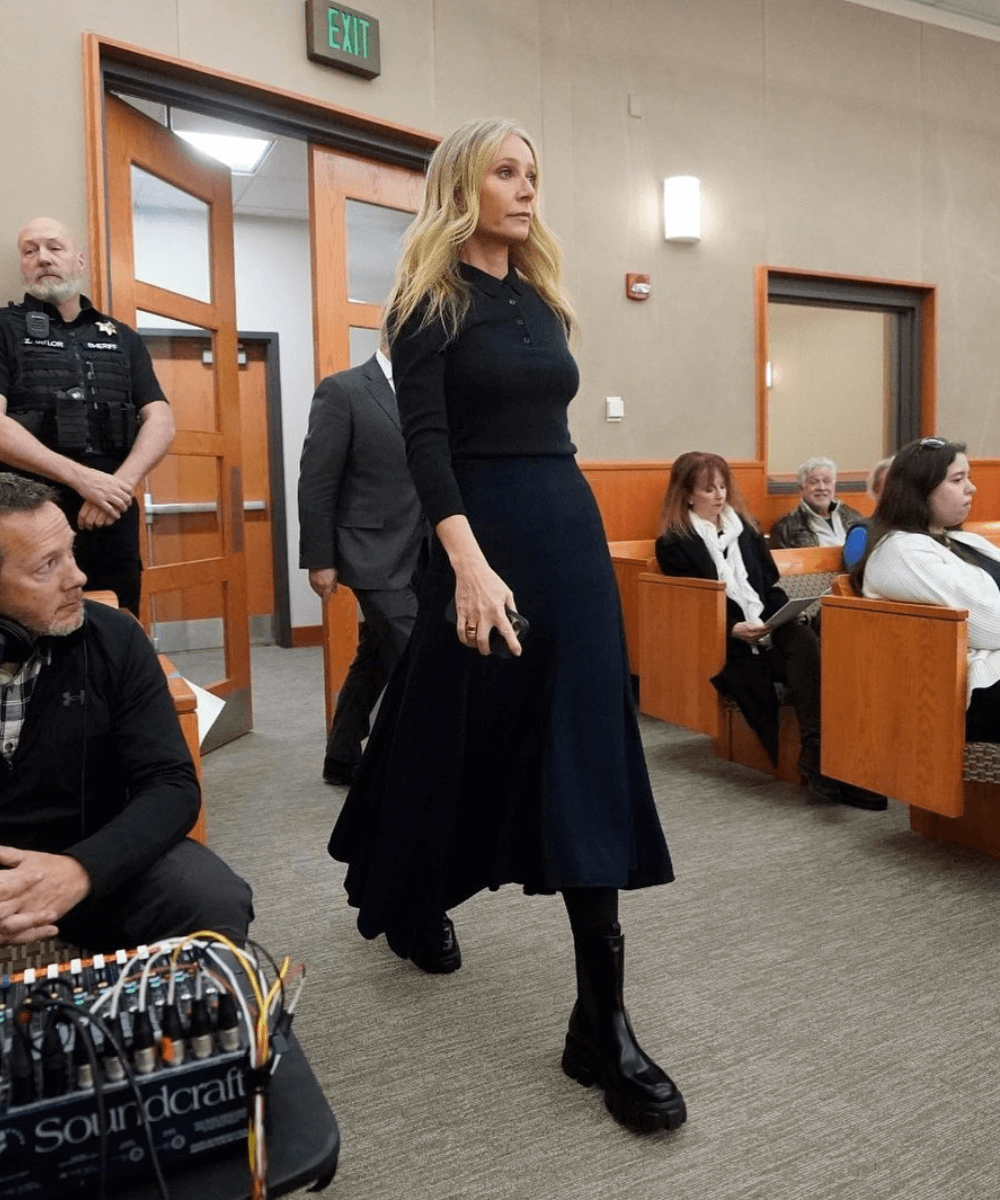 Gwyneth Paltrow - saia longa preta, blusa de mangas longas preta e botas tratoradas - Quiet Luxury - inverno - andando em uma sala - https://stealthelook.com.br
