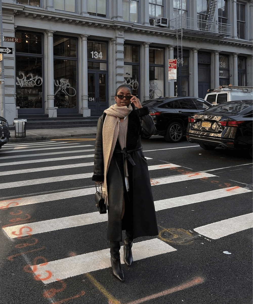 @itsdemib - casaco longo preto, botas pretas e óculos de sol - inverno 2023 - inverno - em pé no meio da rua - https://stealthelook.com.br