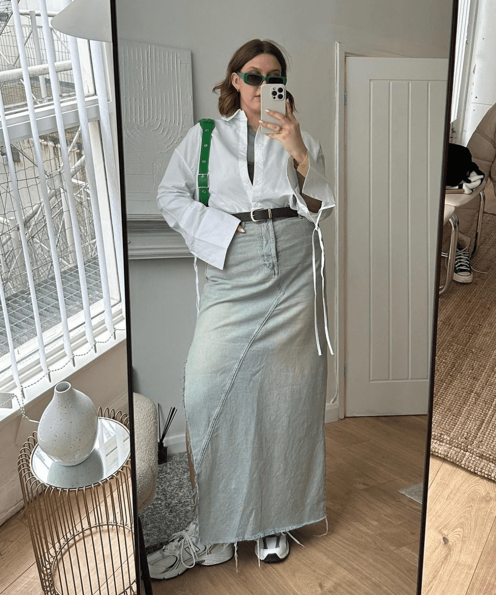Madison Eley - saia longa jeans, camisa branca, tenis esportivo, bolsa verde e óculos de sol - looks com tênis branco - outono - foto na frente do espelho - https://stealthelook.com.br