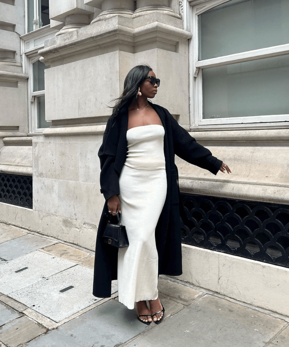 Rabia Cissokho - vestido longo off white, sobretudo preto e sandálias - looks de festa - inverno - em pé na rua - https://stealthelook.com.br