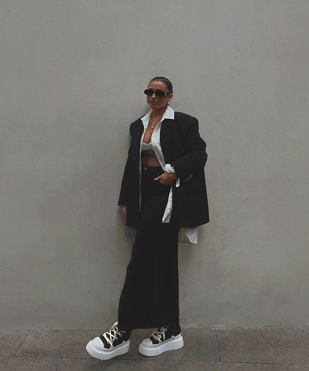 Faye Queenan - calça preta de alfaiataria, camisa branca, blazer oversized e all star preto - inverno 2023 - inverno - mulher em pé na rua - https://stealthelook.com.br