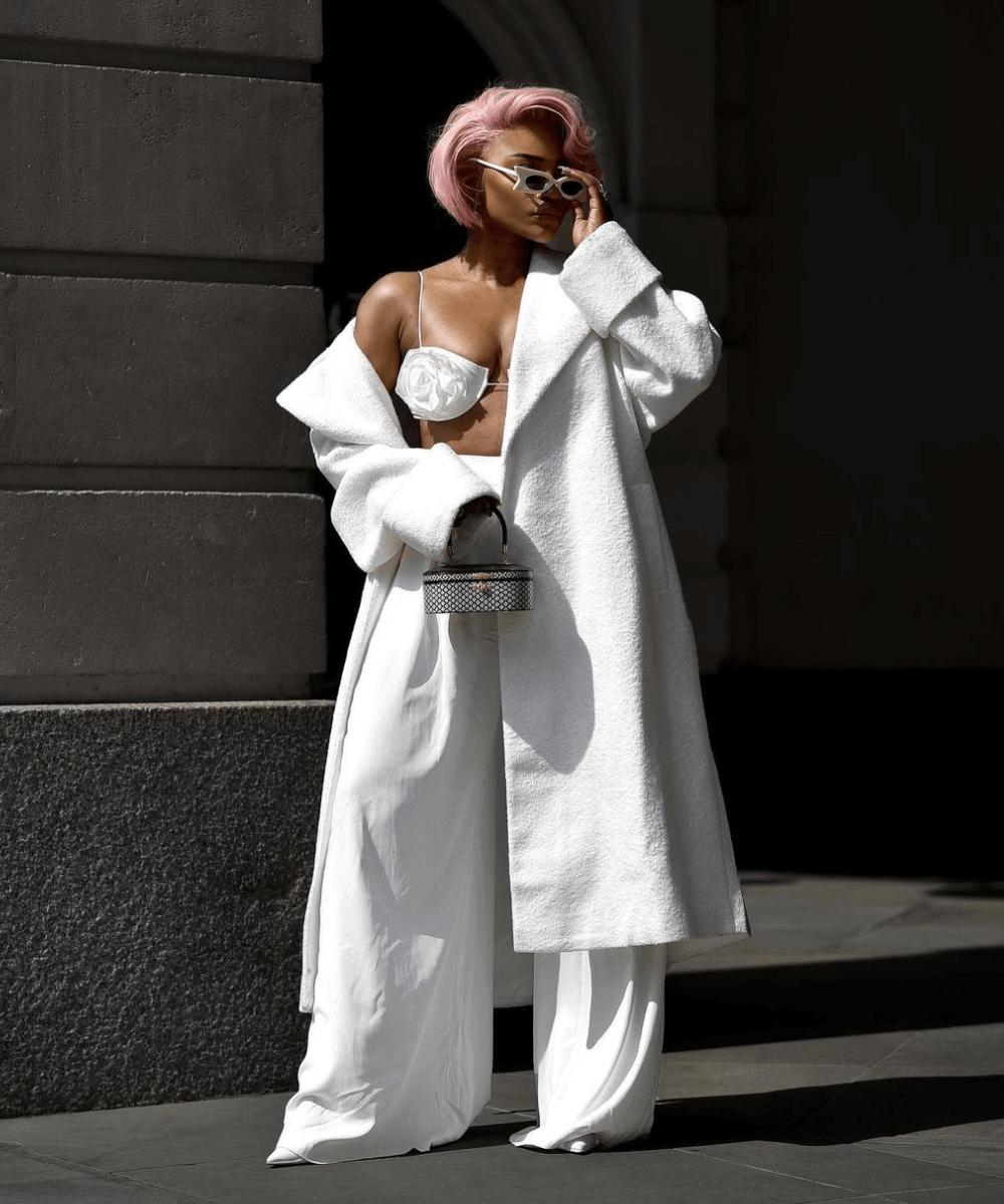 Juliette Foxx - calça pantalona branca, top de flores e sobretudo branco - inverno 2023 - inverno - mulher de cabelo rosa em pé na rua - https://stealthelook.com.br