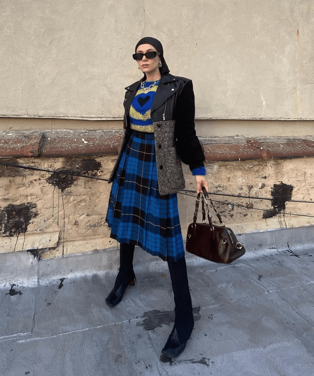 @noore - legging preta, saia xadrez midi, tricot e jaqueta de couro preta - tendência de 2023 - inverno - mulher em pé na rua usando óculos de sol - https://stealthelook.com.br