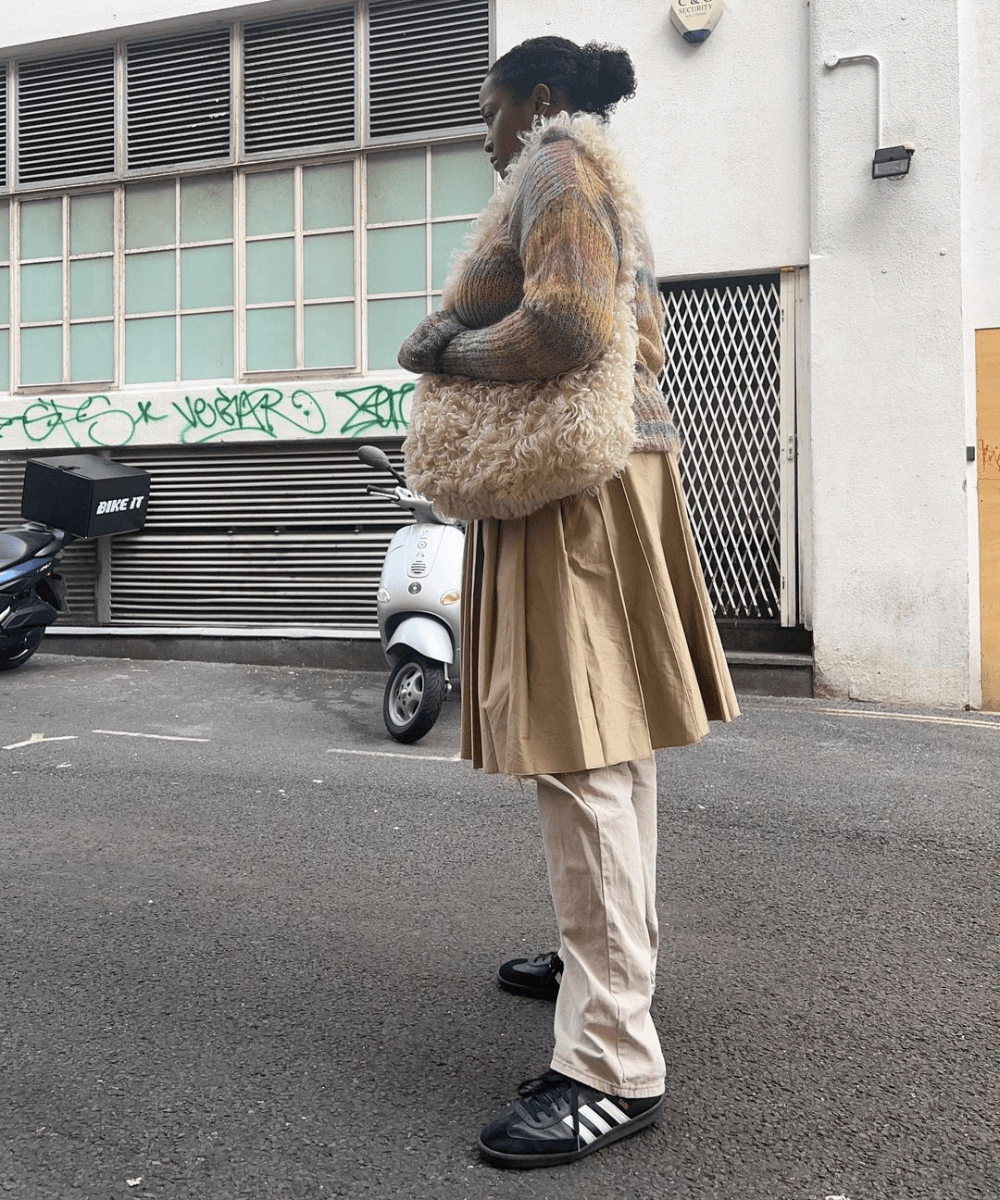 @champagnemani | Imani Randolph - calça cargo bege, saia plissada midi e jaqueta estampada - tendência de 2023 - inverno - mulher de lado em pé na rua - https://stealthelook.com.br