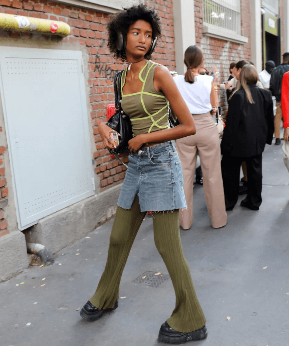 Street Style de Milão - calça verde, minissaia jeans e blusa verde - tendência de 2023 - outono - mulher andando na rua - https://stealthelook.com.br