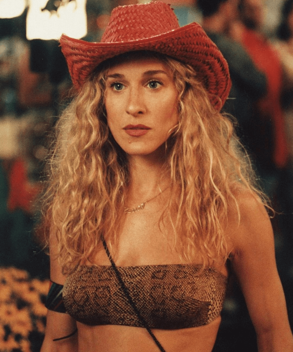 Carrie Bradshaw - top sem alças, chapéu de cowboy vermelho - Sex and The City - verão - foto de close da personagem na praia usando um chapéu vermelho - https://stealthelook.com.br