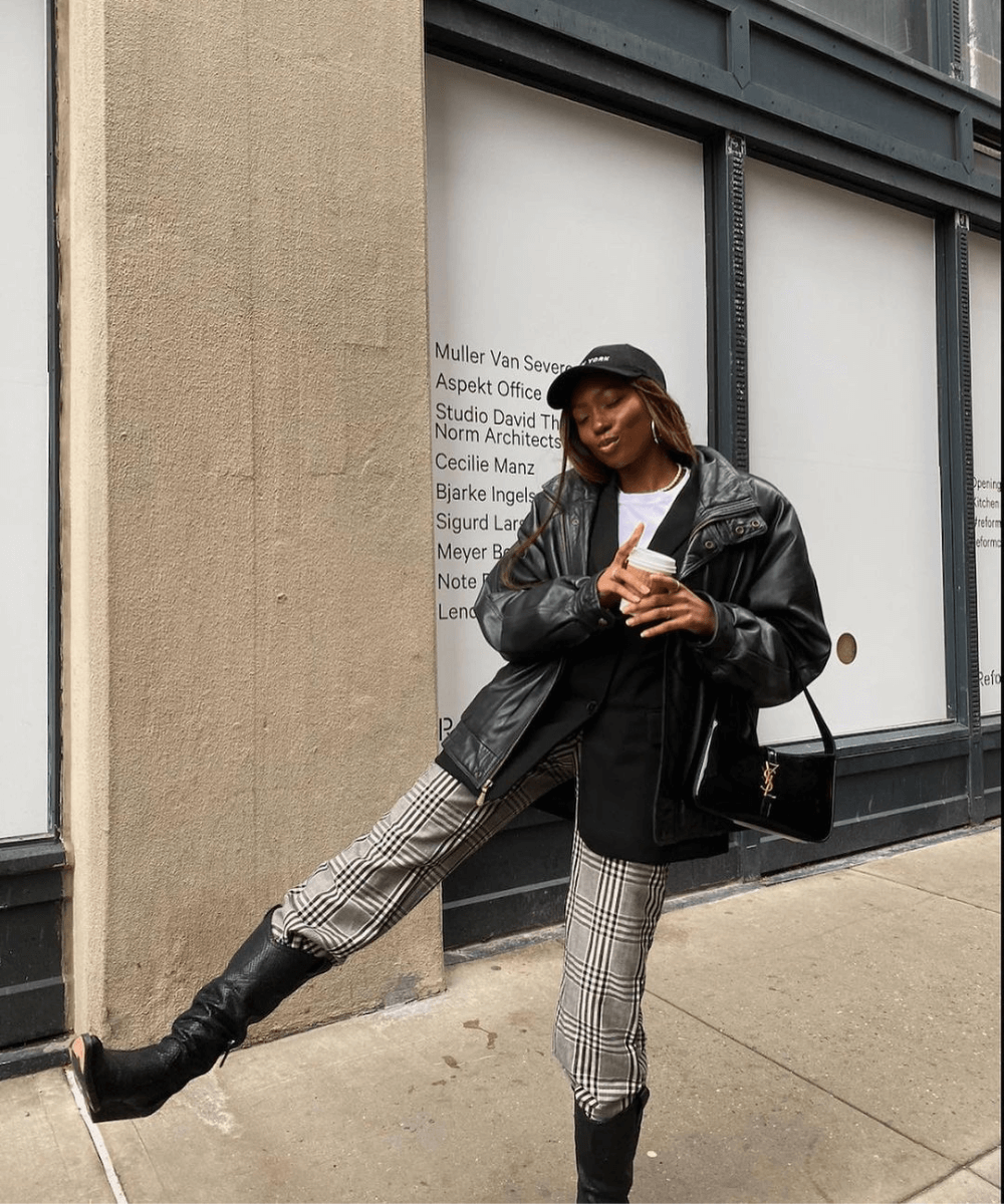 Chanel Mckinsie - calça estampada, bota de cano longo, jaqueta de couro preta e bone - bota de cano longo - inverno - em pé na rua - https://stealthelook.com.br
