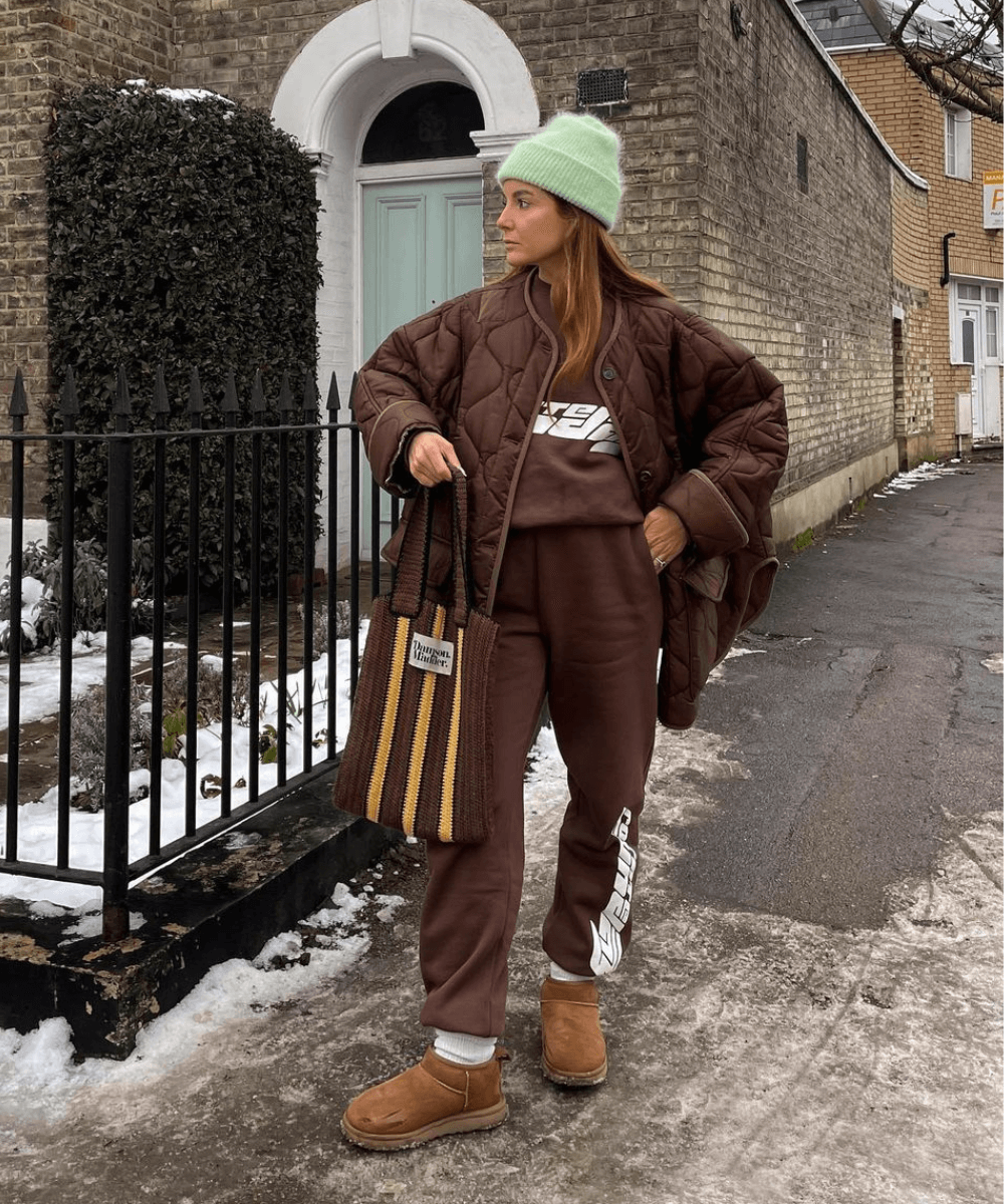 @rebeccaferrazwyatt - conjunto de moletom marrom, jaqueta puffer marrom, gorro verde e bota ugg - looks de inverno - inverno - mulher em pé na rua olhando para o lado - https://stealthelook.com.br