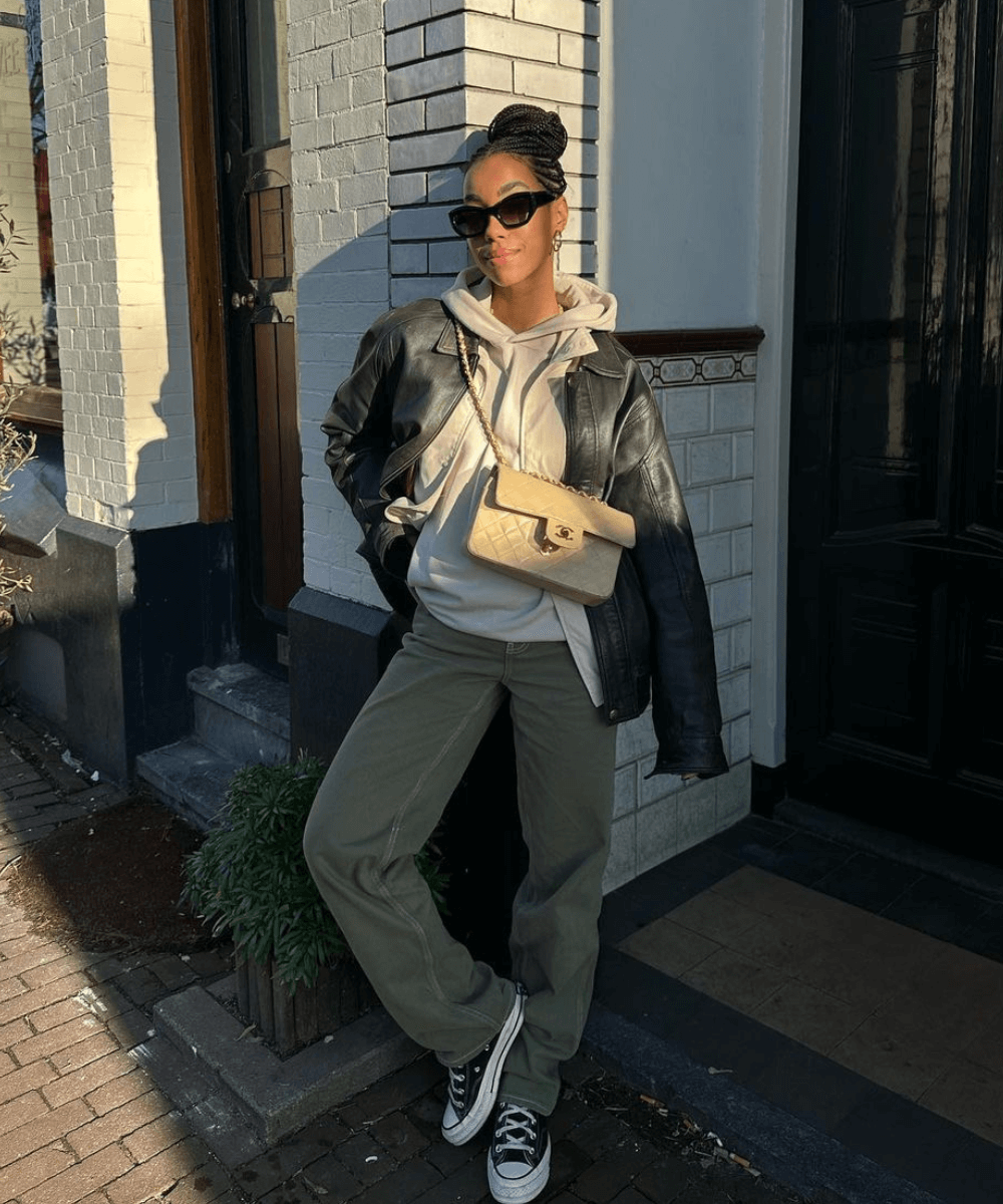 Amaka Hamelijnck - calça verde cargo, moletom, jaqueta de couro preta e tênis - inverno 2023 - inverno - mulher em pé na rua usando óculos de sol - https://stealthelook.com.br