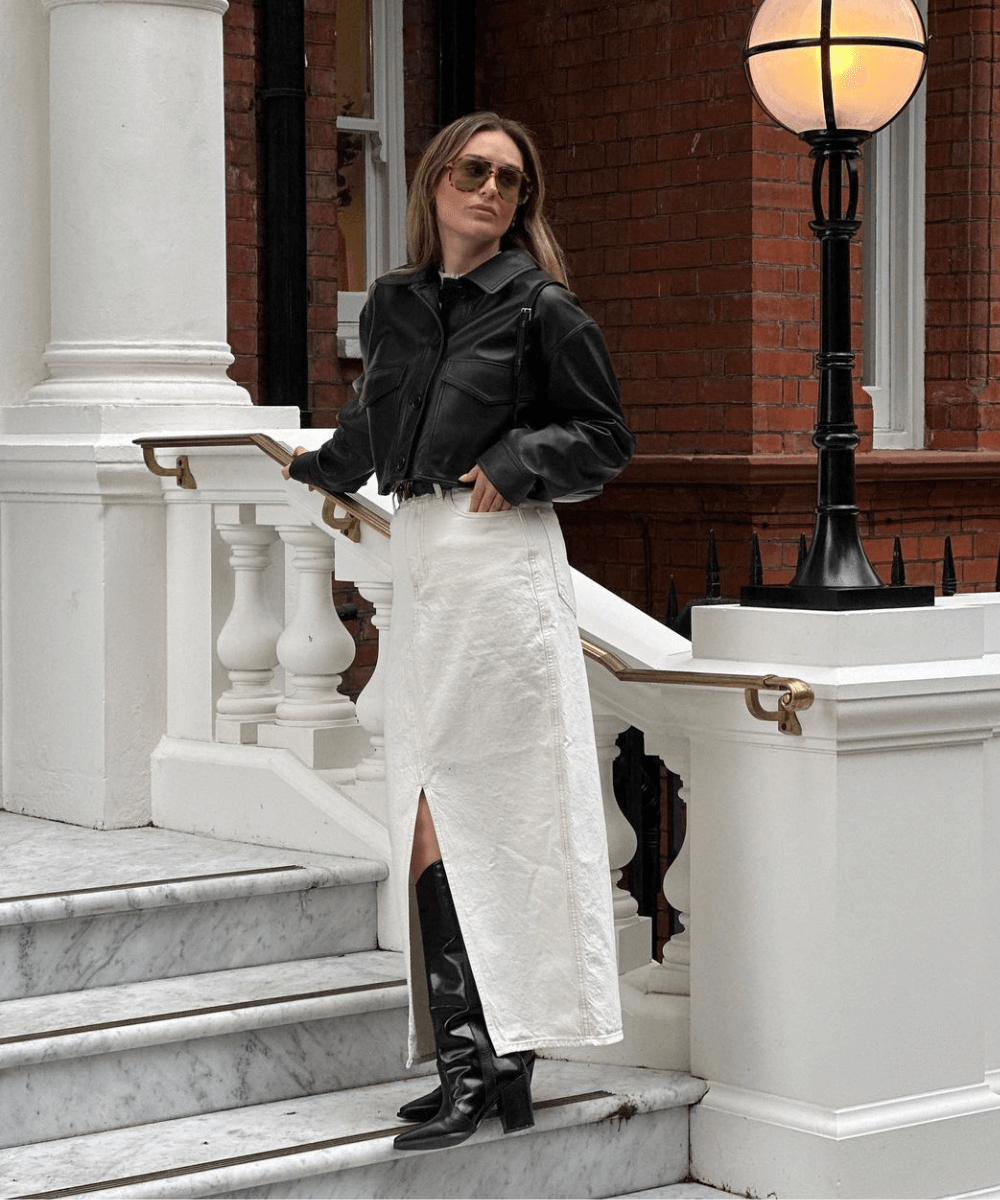 Olivia Faeh - saia midi branca, jaqueta de couro preta e botas de cano longo pretas - saia midi - inverno - mulher de óculos em pé na rua - https://stealthelook.com.br