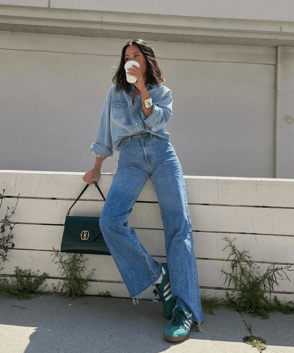 Aimee Song - calça jeans, camisa jeans, tênis adidas verde e bolsa verde - looks de festa junina - outono - em pé na rua tomando um café - https://stealthelook.com.br