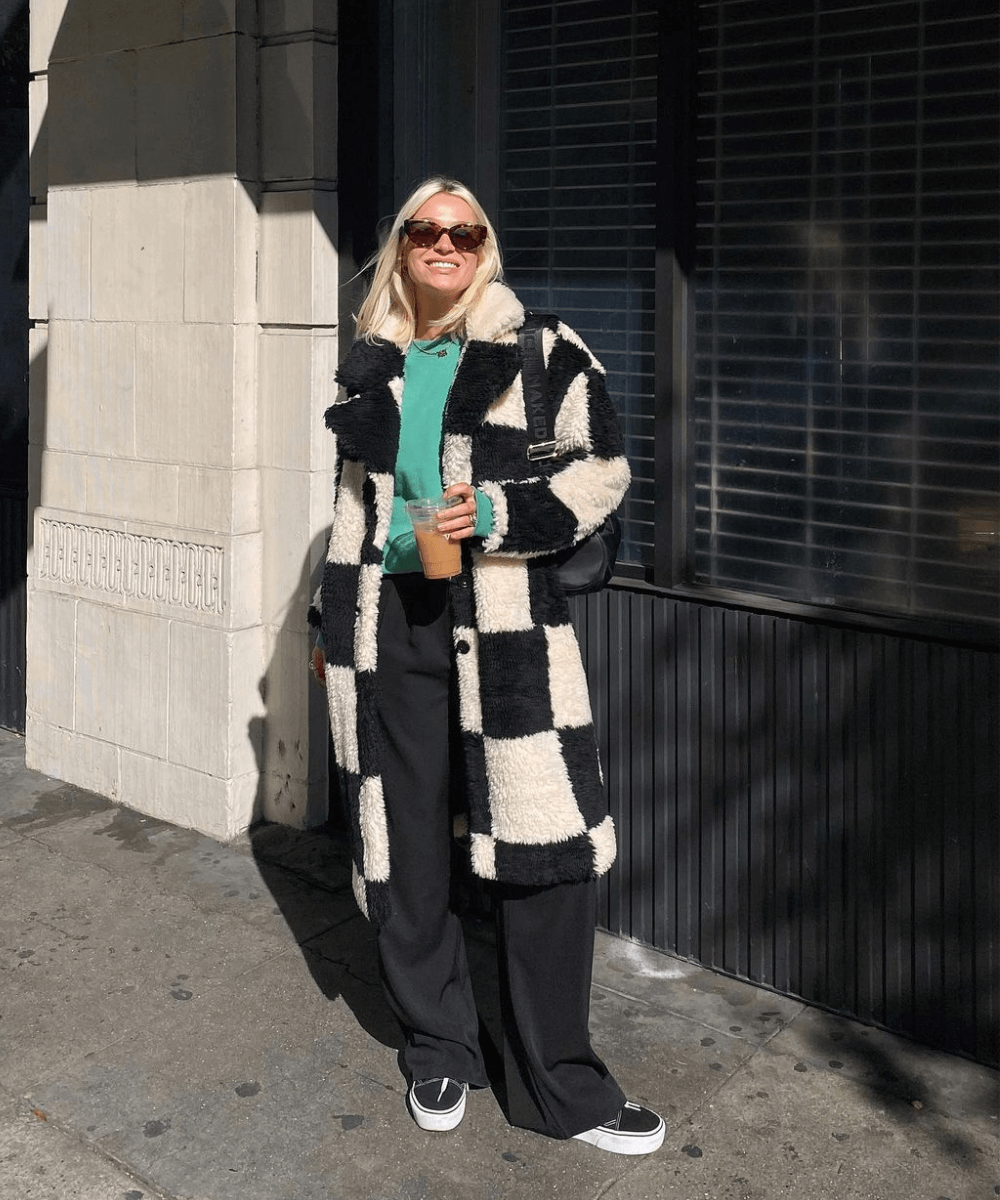 @marthaeelman - calça preta, moletom verde, casaco longo xadrez e tênis vans preto - looks de festa junina - inverno - mulher loira andando na rua usando óculos de sol - https://stealthelook.com.br