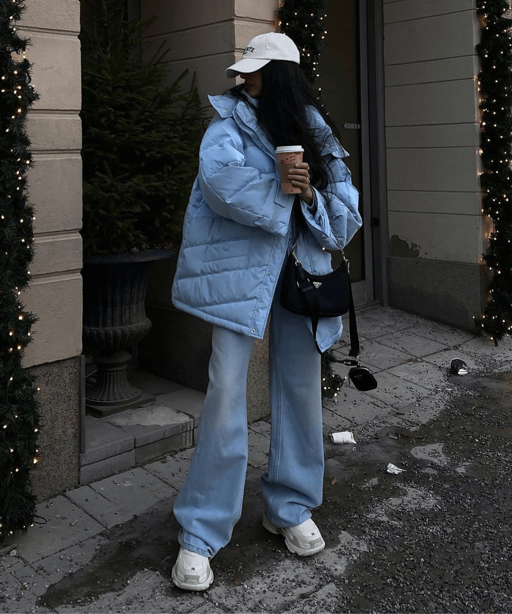 @narrinanatasha - calça jeans wide leg, jaqueta puffer azul, tênis e boné bege - looks de inverno - inverno - mulher em pé na rua segurando um café na mão  - https://stealthelook.com.br