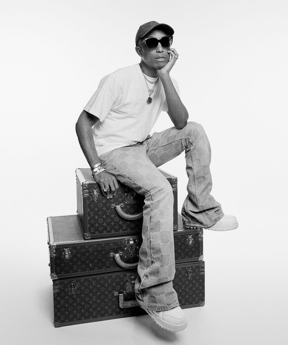 Pharrell Williams - t-shirt branca, óculos de sol e jeans - Pharrell Williams - primavera - foto em preto e branco, com o cantor sentado em três malas da Louis Vuitton - https://stealthelook.com.br