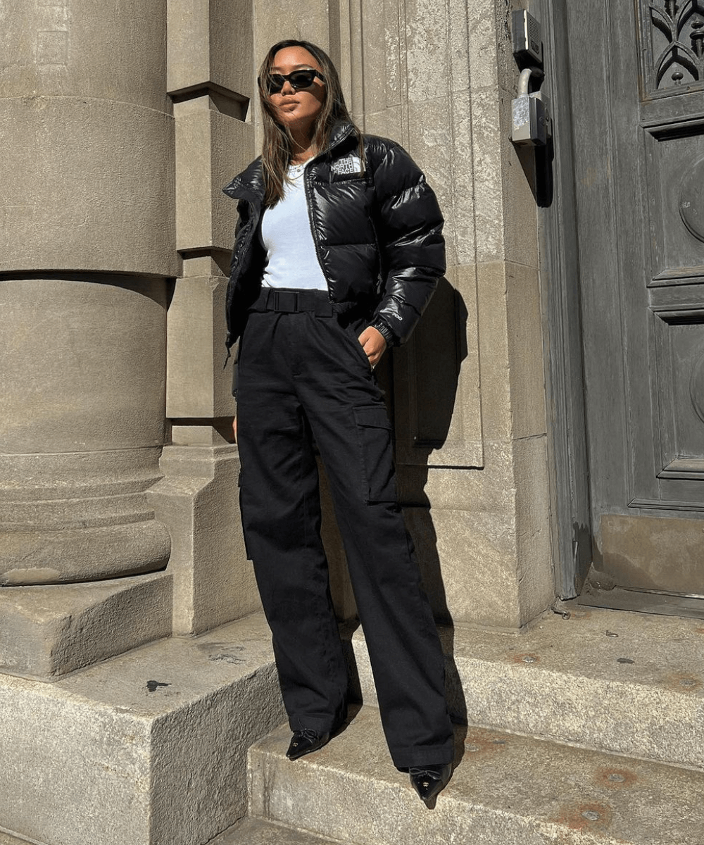 Linh Niller - calça preta, jaqueta puffer preta, bota preta e óculos de sol escuros - looks com jaqueta puffer - inverno - mulher andando na rua usando óculos de sol - https://stealthelook.com.br