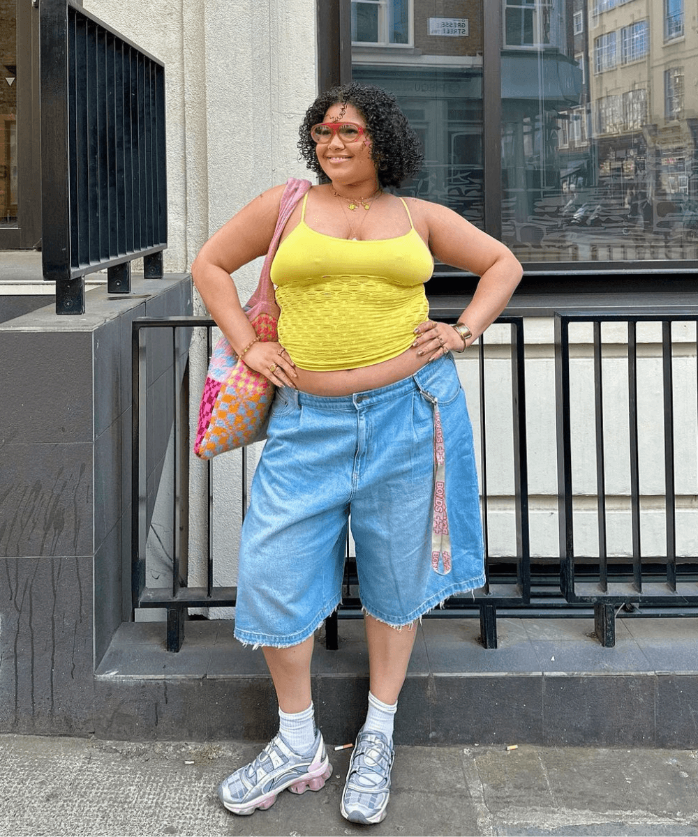 um homem de cabelo branco usa colete e short jeans vermelho sapato de pé e  segurando