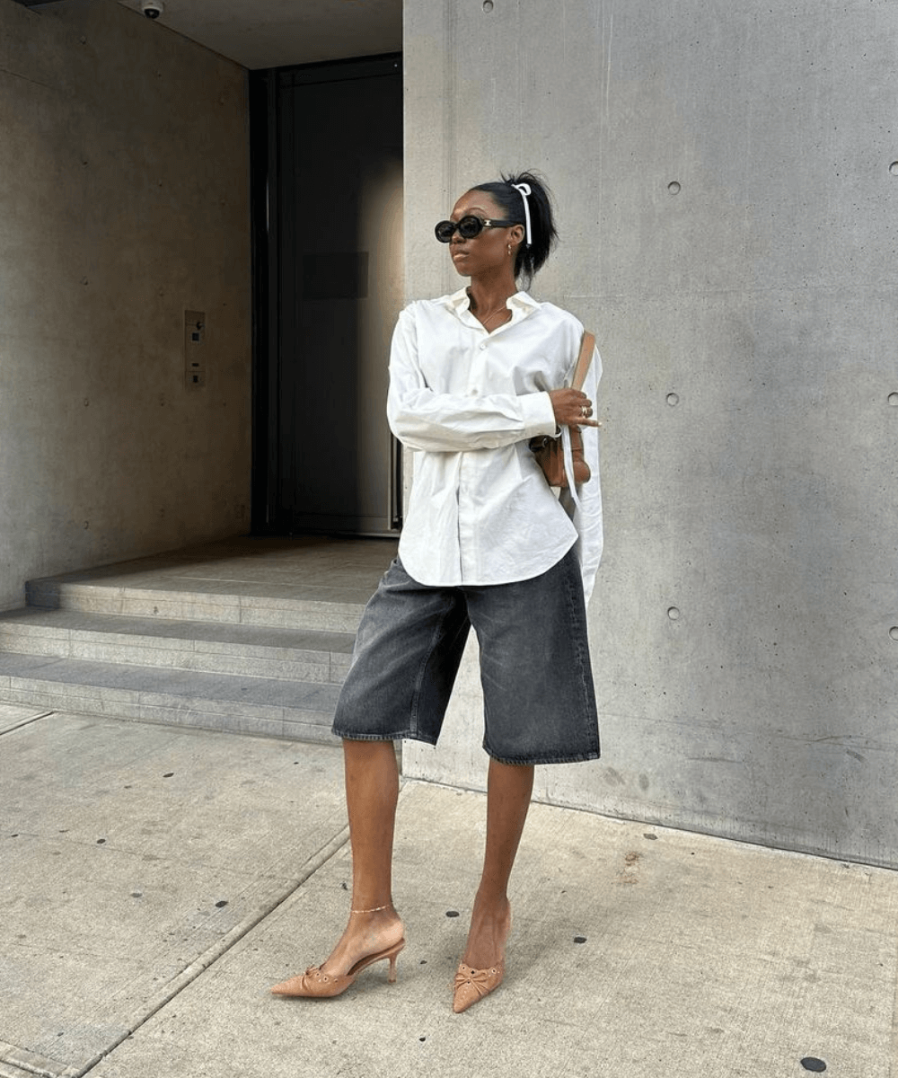 Chanel Mckinsie - bermuda jeans, salto de scarpin e camisa branca oversized - tendência de moda - verão - mulher negra em pé na rua usando óculos de sol - https://stealthelook.com.br
