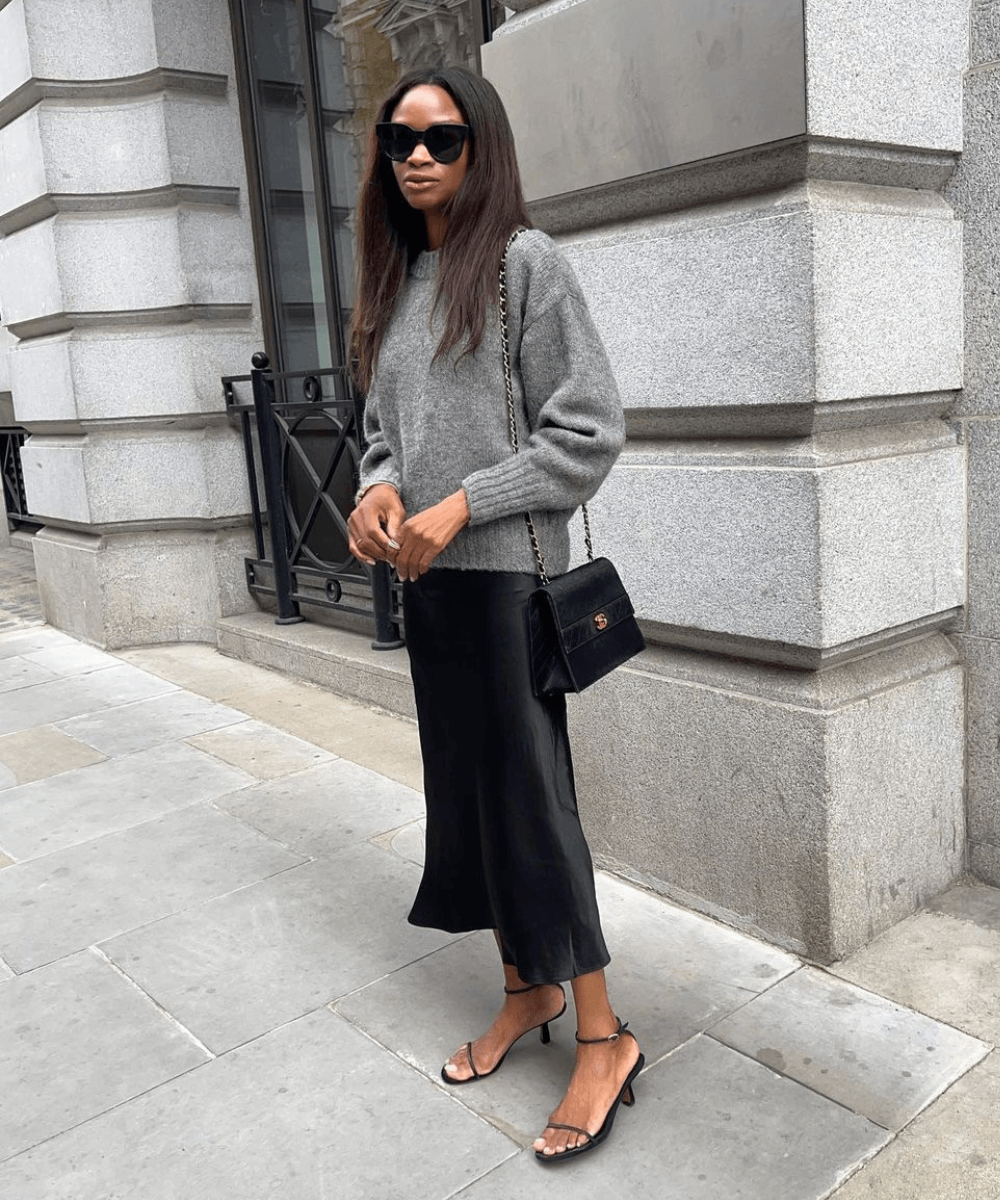 @symphonyofsilk - saia midi preta, trico cinza e sandália preta - looks com tricô - inverno - mulher em pé na rua usando óculos de sol - https://stealthelook.com.br