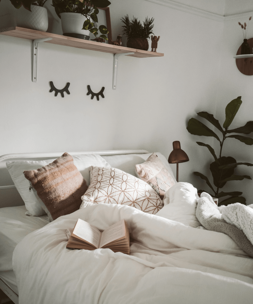 Taryn Elliott -     - itens de decoração - inverno - foto de uma cama com colcha branca, almofadas e um livro aberto em cima - https://stealthelook.com.br