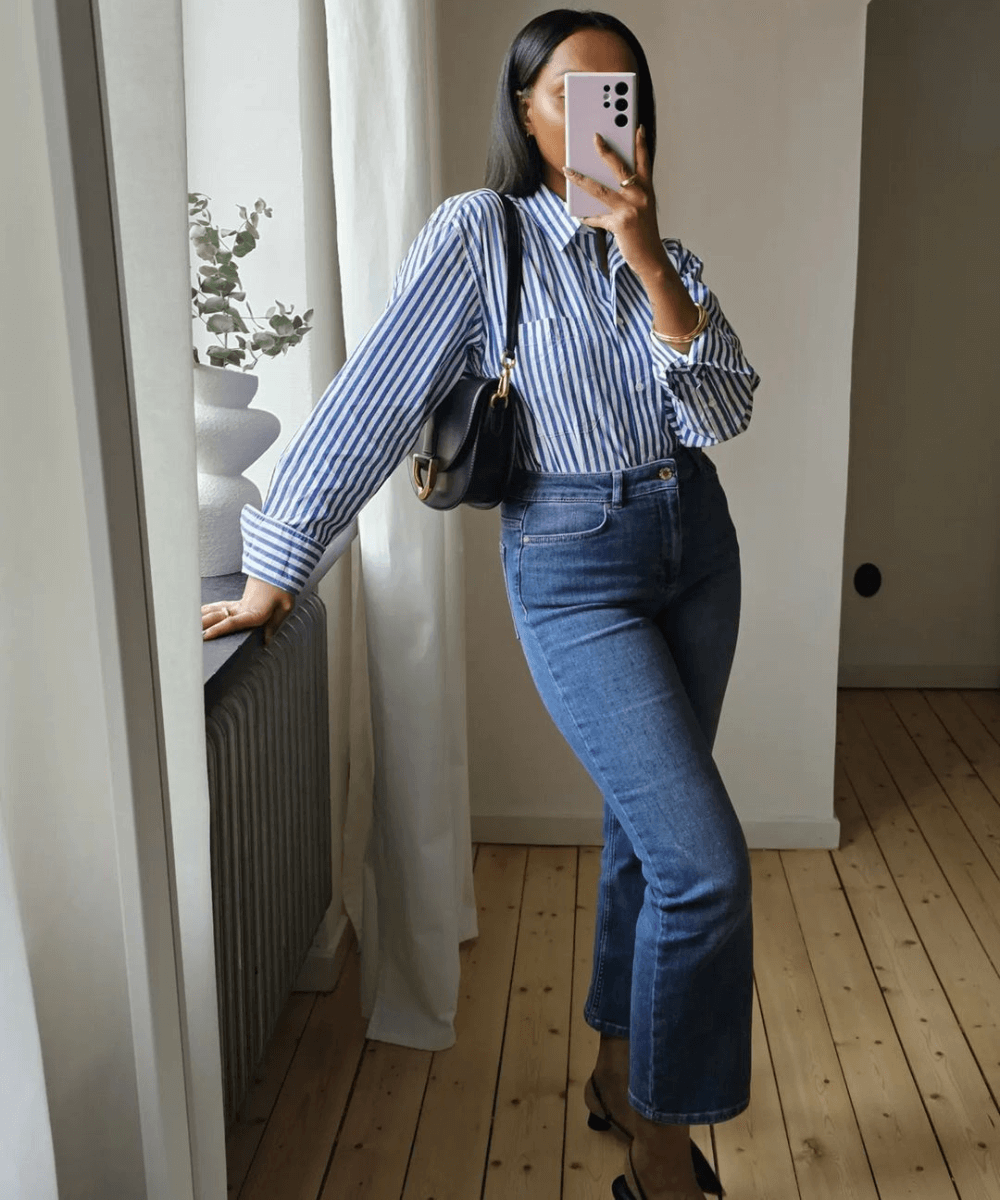@femmeblk - calça jeans, camisa social azul listrada, bolsa preta e sapato preto de salto - looks com jeans - outono - mulher negra tirando foto no espelho - https://stealthelook.com.br