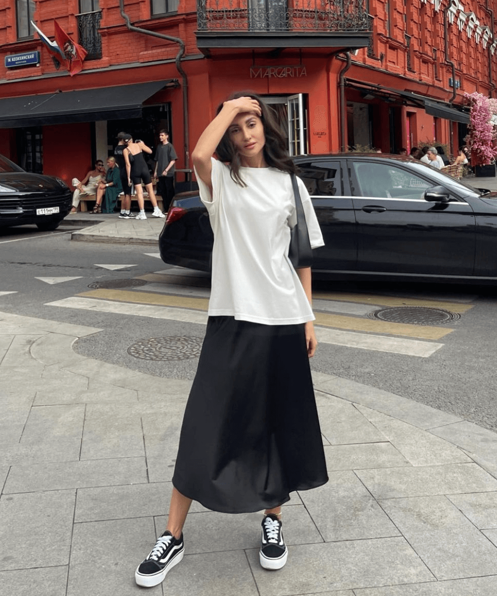 @prosto.sapi - t-shirt oversized branca, saia midi preta e tênis vand old skool - tênis da moda - verão - mulher em pé na rua com a mão na cabeça - https://stealthelook.com.br