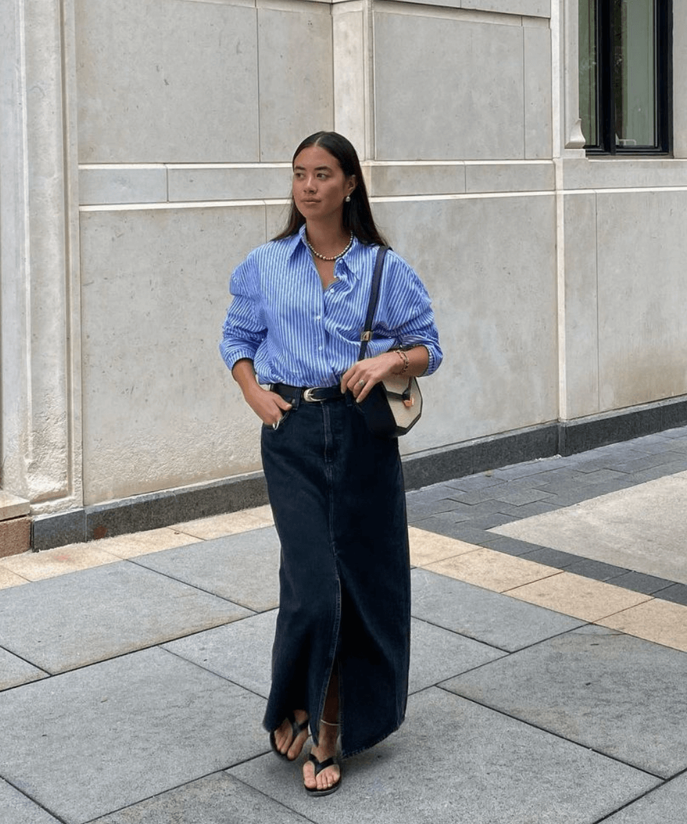 Sasha Mei - saia longa jeans, camisa azul oversized, sapato preto e bolsa preta - looks básicos - outono - mulher asiática em pé na rua - https://stealthelook.com.br