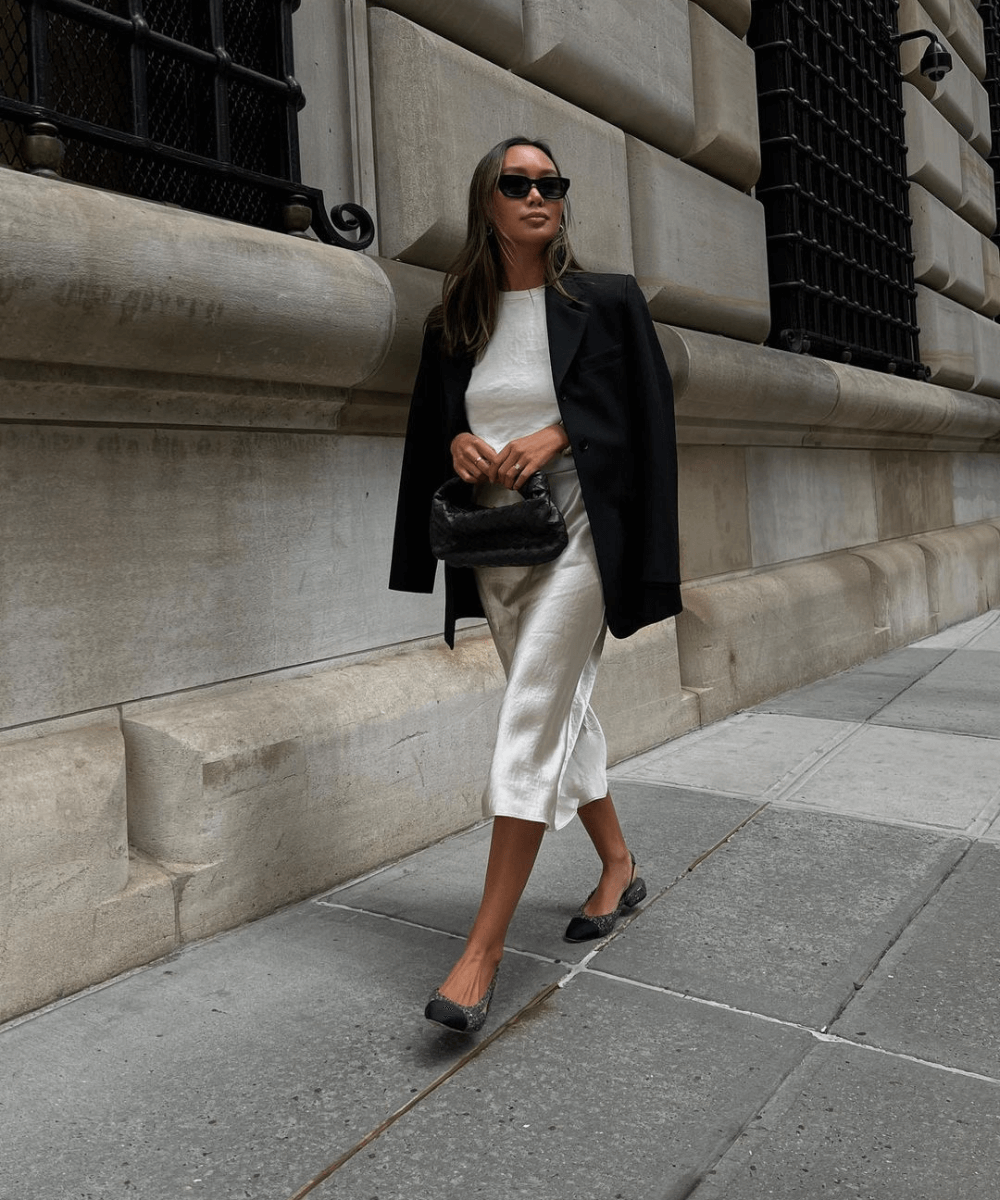 Linh Niller - saia midi acetinada, cropped branco e blazer preto. - look de trabalho - inverno - mulher asiática de óculos andando na rua - https://stealthelook.com.br