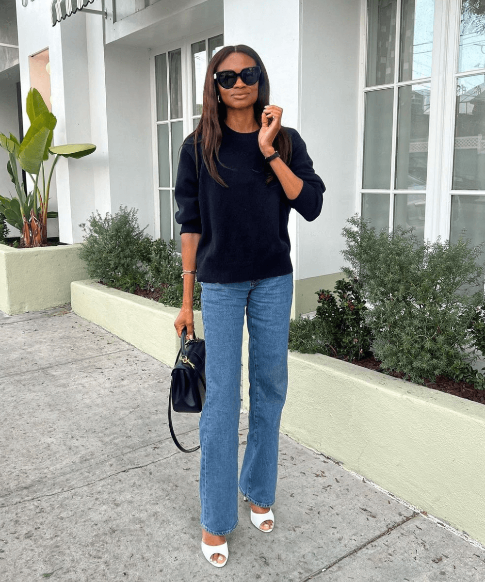 @symphonyofsilk - calça jeans reta, sandália de salto e tricot azul marinho - look de trabalho - outono - mulher negra em pé na rua usando óculos de sol e segurando uma bolsa - https://stealthelook.com.br