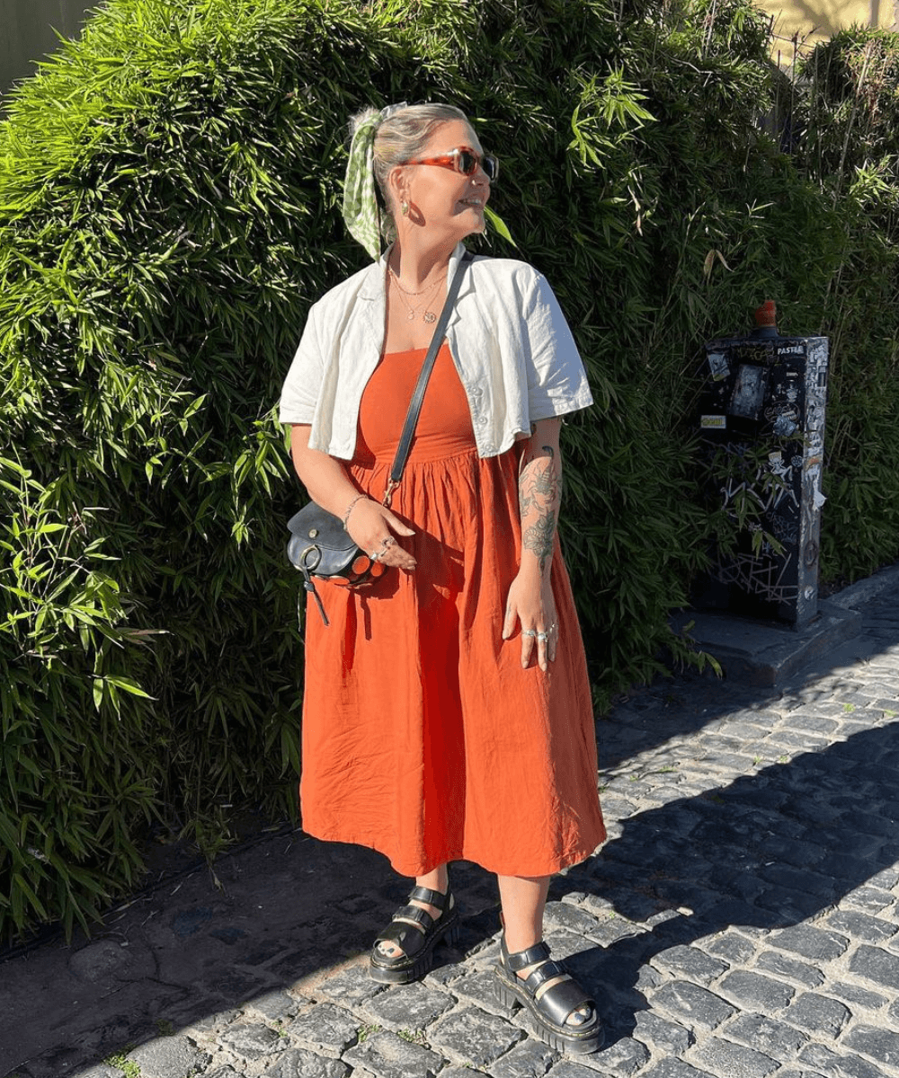 Libby Faulkner - vestido midi laranja, camisa branca curta e sandália de plataforma preta - look de trabalho - verão - mulher loira em pé na rua usando óculos de sol e olhando para o lado - https://stealthelook.com.br