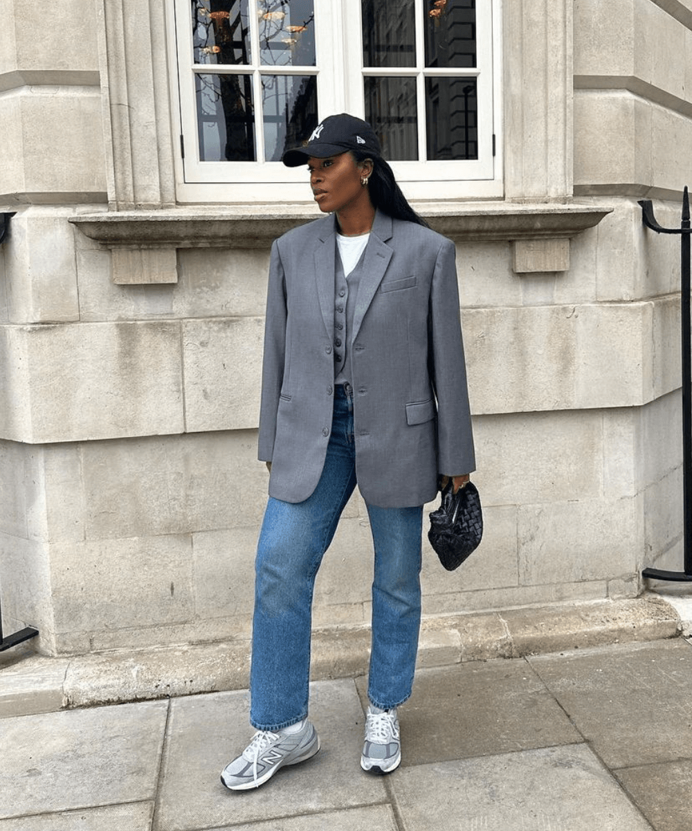@nlmarilyn - calça jeans reta, blazer oversized cinza, boné e tênis esportivo branco - tendência de moda - outono - mulher negra em pé na rua usando um boné - https://stealthelook.com.br