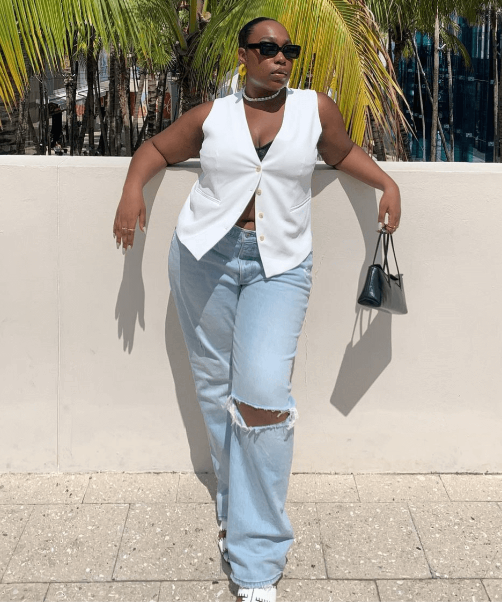 Aniyah Morinia - calça jeans, colete branco, sandália fisherman - tendência de moda - verão - mulher negra em pé na rua usando óculos de sol - https://stealthelook.com.br