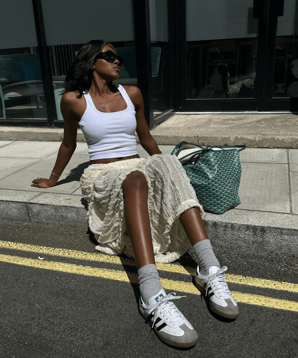 @georgia_3.0 - saia midi de babados, regata branca, adidas samba e óculos de sol - tênis da moda - verão - mulher negra sentada na rua usando um óculos de sol - https://stealthelook.com.br