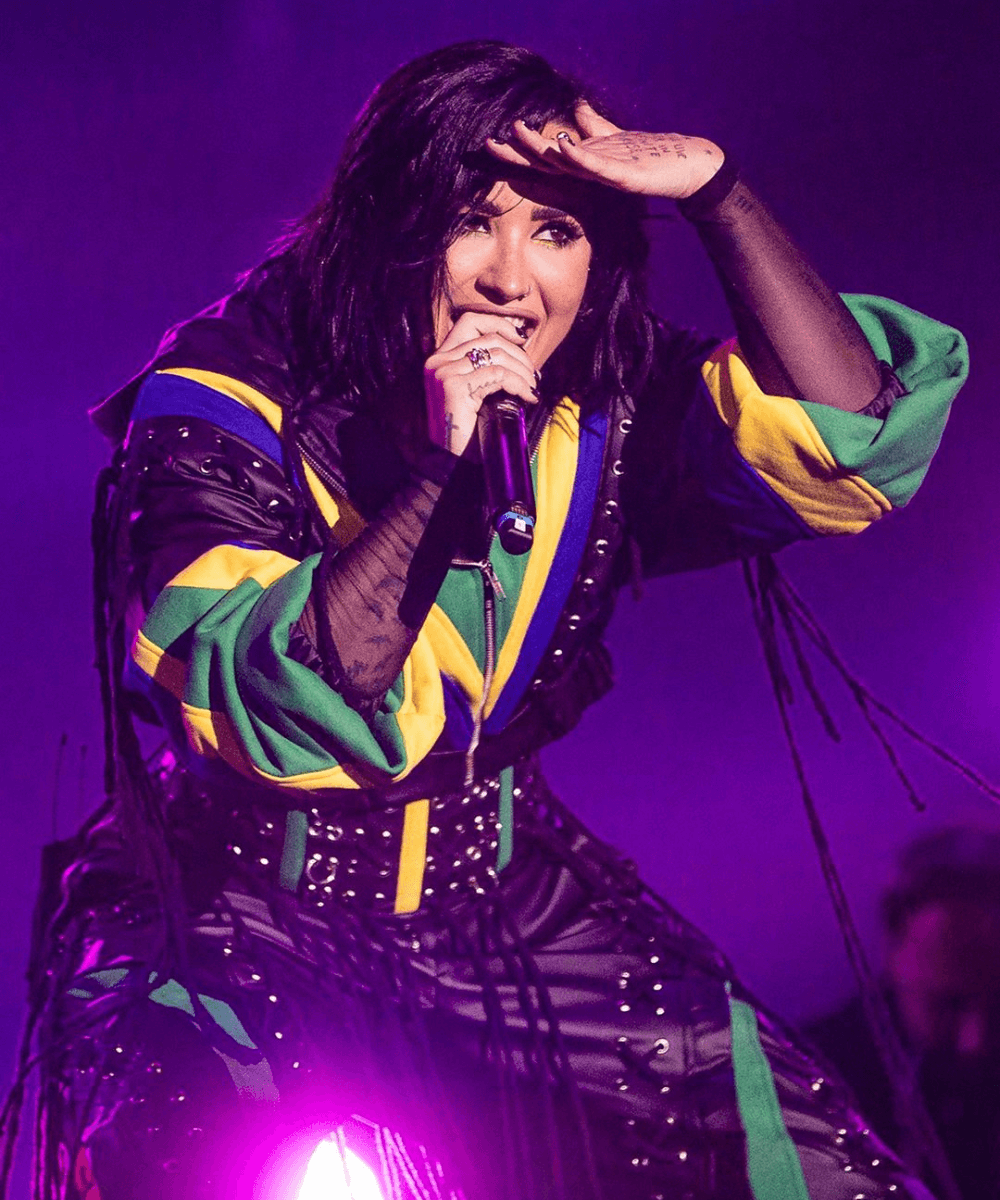 Demi Lovato - macacão preto com as cores do Brasil - The Town - inverno - cantora em cima do palco se apresentando - https://stealthelook.com.br
