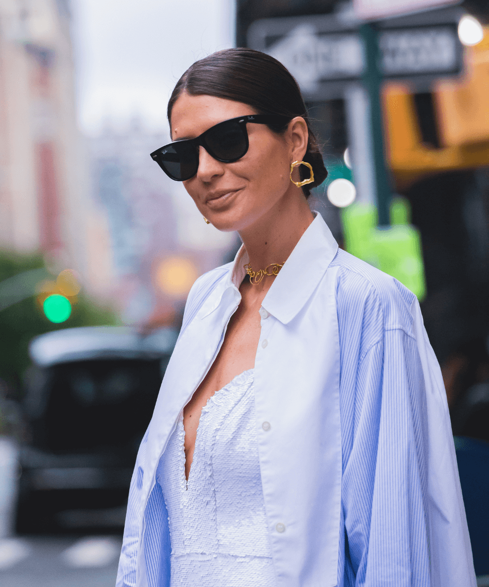 Manuela Bordasch - vestido slip dress e camisa oversized branca - looks da fashion week - verão - mulher sorrindo em pé na rua usando um óculos de sol - https://stealthelook.com.br