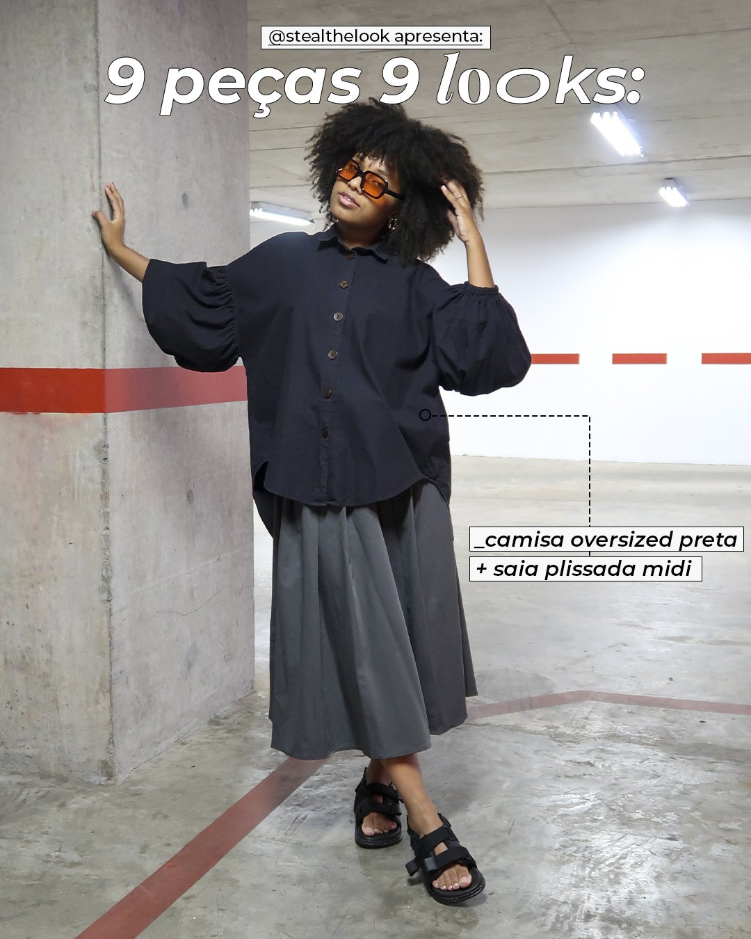 Clau Ribeiro - saia midi cinza, camisa oversized preta e mocassim - looks básicos - inverno - mulher negra de óculos sorrindo parada em pé em uma garagem - https://stealthelook.com.br