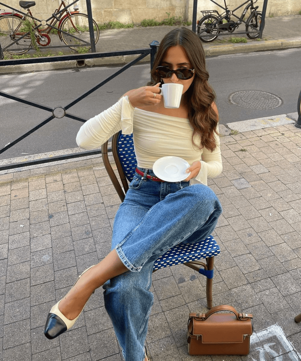 @florettenacer - calça jeans, sapatilha e blusa drapeada off white - anos 2000 - verão - mulher sentada em um café bebendo em uma xícara e usando óculos de sol - https://stealthelook.com.br