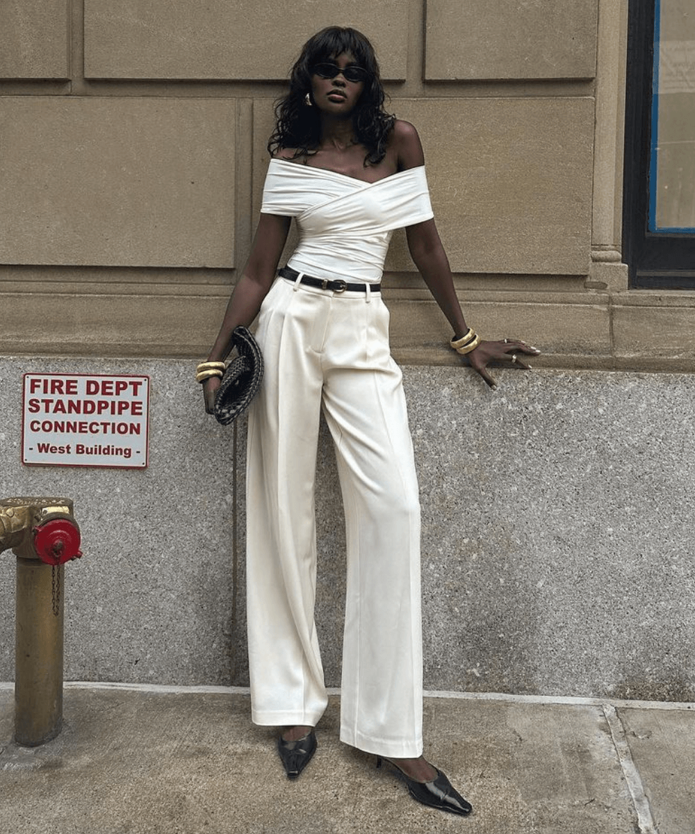 Amy Julliette Lefévre - calça branca, blusa drapeada ombro a ombro e óculos de sol preto - anos 2000 - verão - mulher negra em pé na rua usando óculos de sol - https://stealthelook.com.br