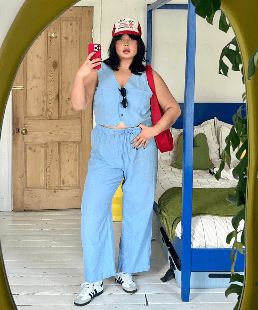 Francesca Perks - conjunto de alfaiataria azul claro, tênis, boné e bolsa vermelha - cor tendência - verão - mulher loira tirando foto na frente do espelho - https://stealthelook.com.br