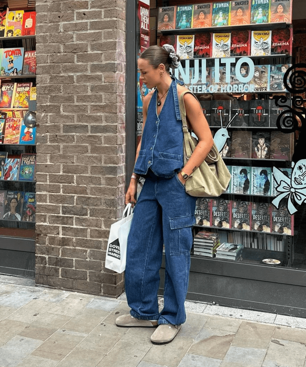 Olivia Hirst - calça cargo jeans, colete jeans e sapato de camurça - tendências de jeans - verão - mulher em pé na rua usando óculos de sol - https://stealthelook.com.br