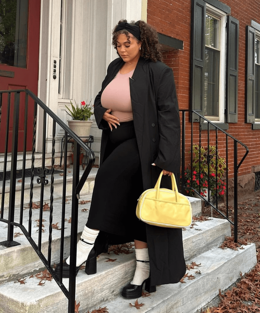 @khloekatera - saia midi preta, meias aparentes, sandália de plataforma, blusa rosa e casaco longo preto - peças-chave estilosas - outono - mulher negra de cabelo cacheado em pé na rua em cima de uma escada - https://stealthelook.com.br