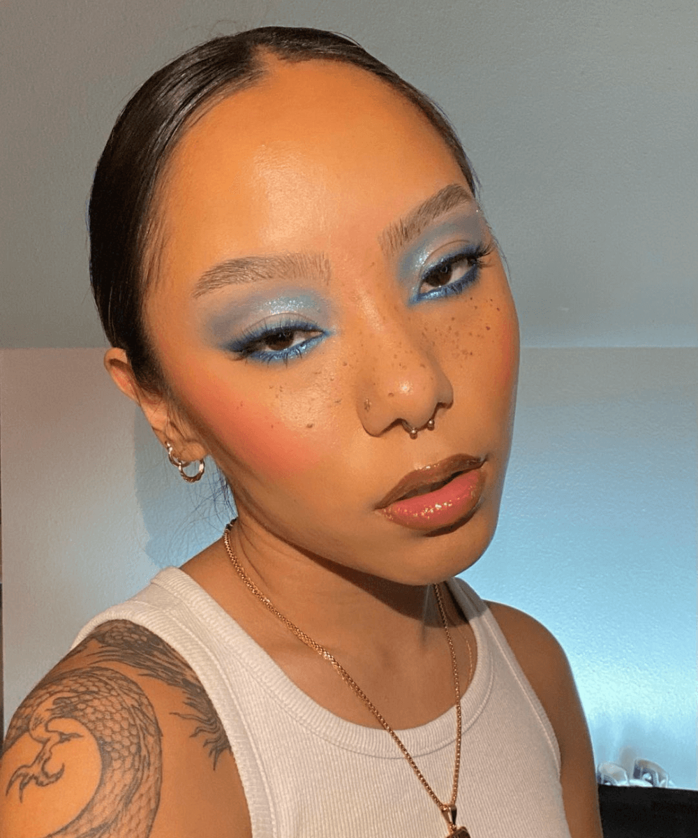 @_chimedolker - regata branca - maquiagem para a the eras tour - verão - foto de close do rosto de uma mulher asiática usando blusa azul - https://stealthelook.com.br