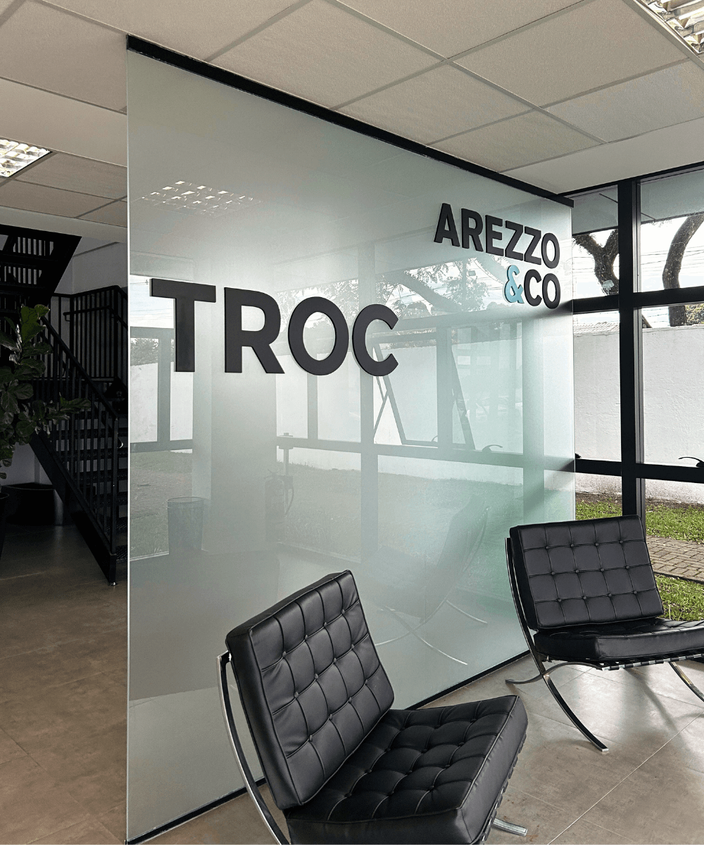 Sede da TROC - N/A - brechó online - primavera - a foto mostra uma sala com duas poltronas pretas, uma parede de vidro com 'TROC' escrito em preto - https://stealthelook.com.br