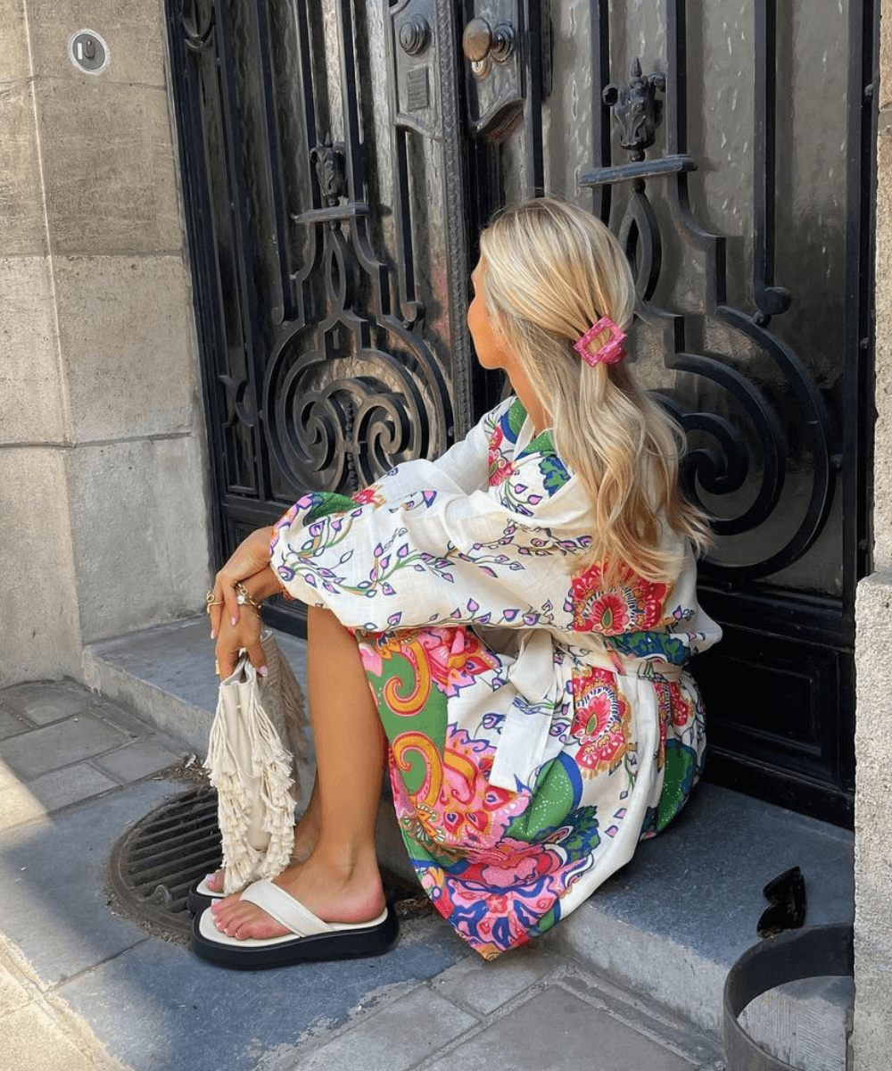 @oliviatps  - vestido curto de mangas longas branco florido - looks com chinelo - verão - mulher loira sentada na rua - https://stealthelook.com.br