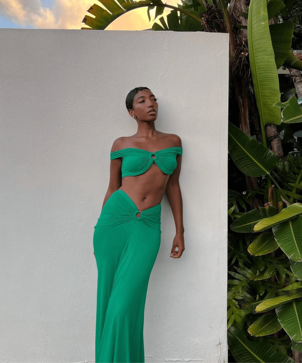 @soleneoj - conjunto de saia longa e cropped top verde - look da virada - verão - mulher negra de pé encostada em uma parede branca - https://stealthelook.com.br