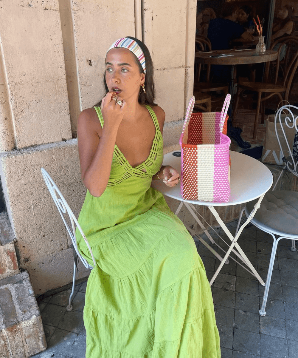 @florettenacer - vestido longo verde, faixa de cabelo colorida e bolsa listrada - look da virada - verão - mulher sentada em um café na rua - https://stealthelook.com.br