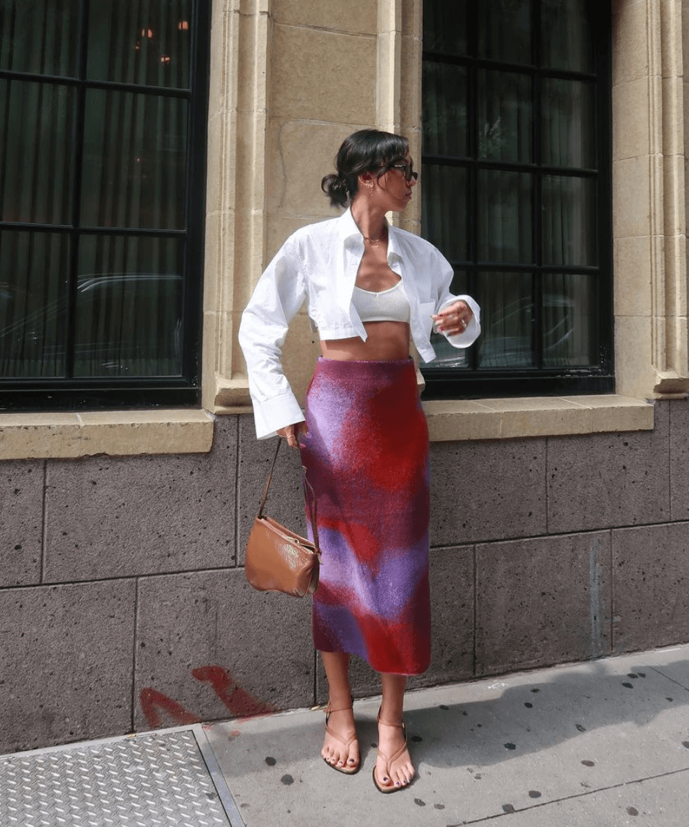 Stephanie Arant - saia midi colorida, top branco e camisa branca - looks com saia midi - verão - mulher em pé na rua - https://stealthelook.com.br