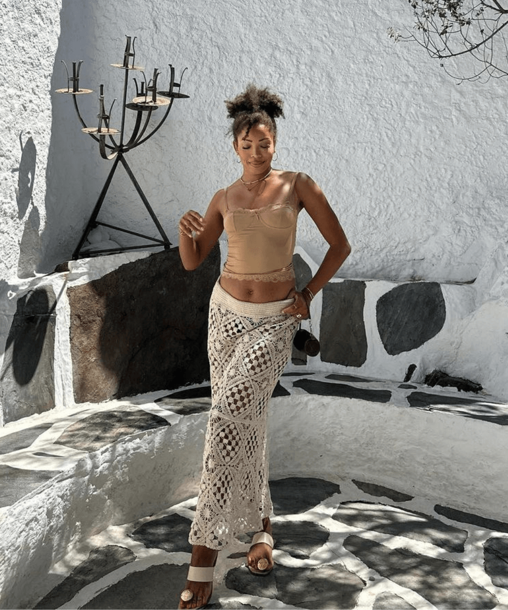 Ellie Delphine - saia de croche, blusa bege e rasteirinha branca - looks de praia - verão - mulher negra em pé na rua - https://stealthelook.com.br