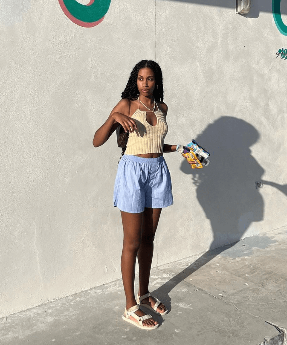 Claire Most - shorts azul, top tricot bege e papete - looks de praia - verão - mulher negra de tranças de pé na rua - https://stealthelook.com.br
