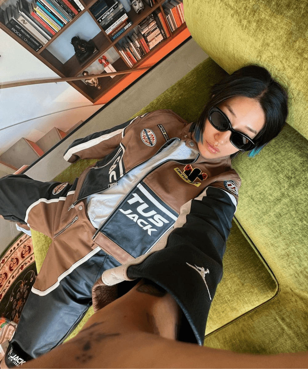Peggy Gou - calça preta, blusa branca e jaqueta de couro - sportswear - outono - mulher asiática de óculos deitada em um sofá tirando foto de cima - https://stealthelook.com.br