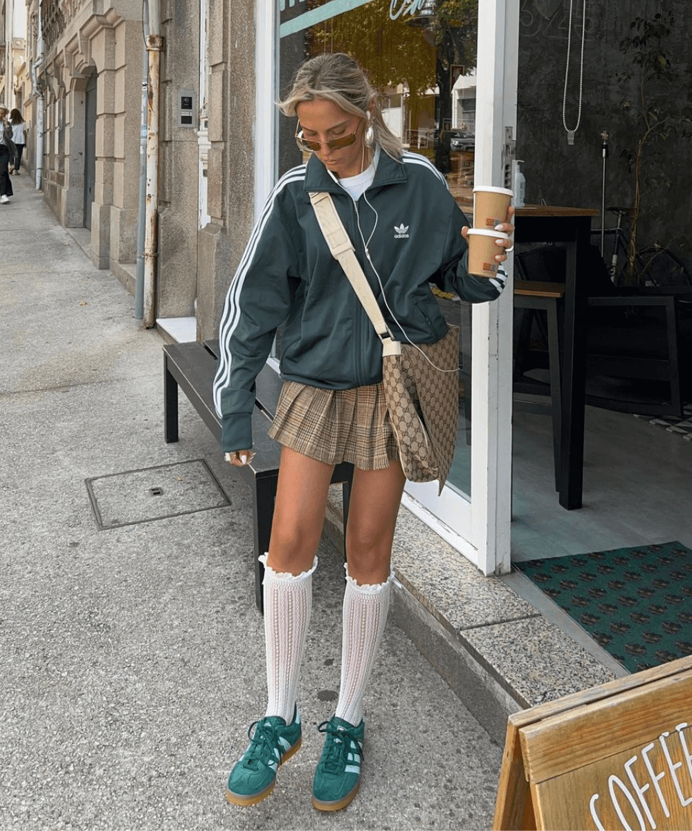 Sofia Coelho - minissaia xadrez, jaqueta verde adidas e tênis verde adidas - sportswear - outono - mulher loira de óculos em pé na rua - https://stealthelook.com.br